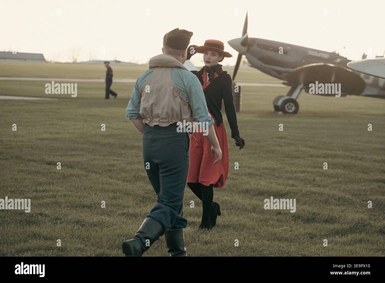 Una donna in abito rosso, cappello e cardigan nero incontra un pilota della RAF accanto a un Hawker Hurricane Mk1 P2902 all'aeroporto Sywell, rievocazione degli anni '1940 Foto Stock