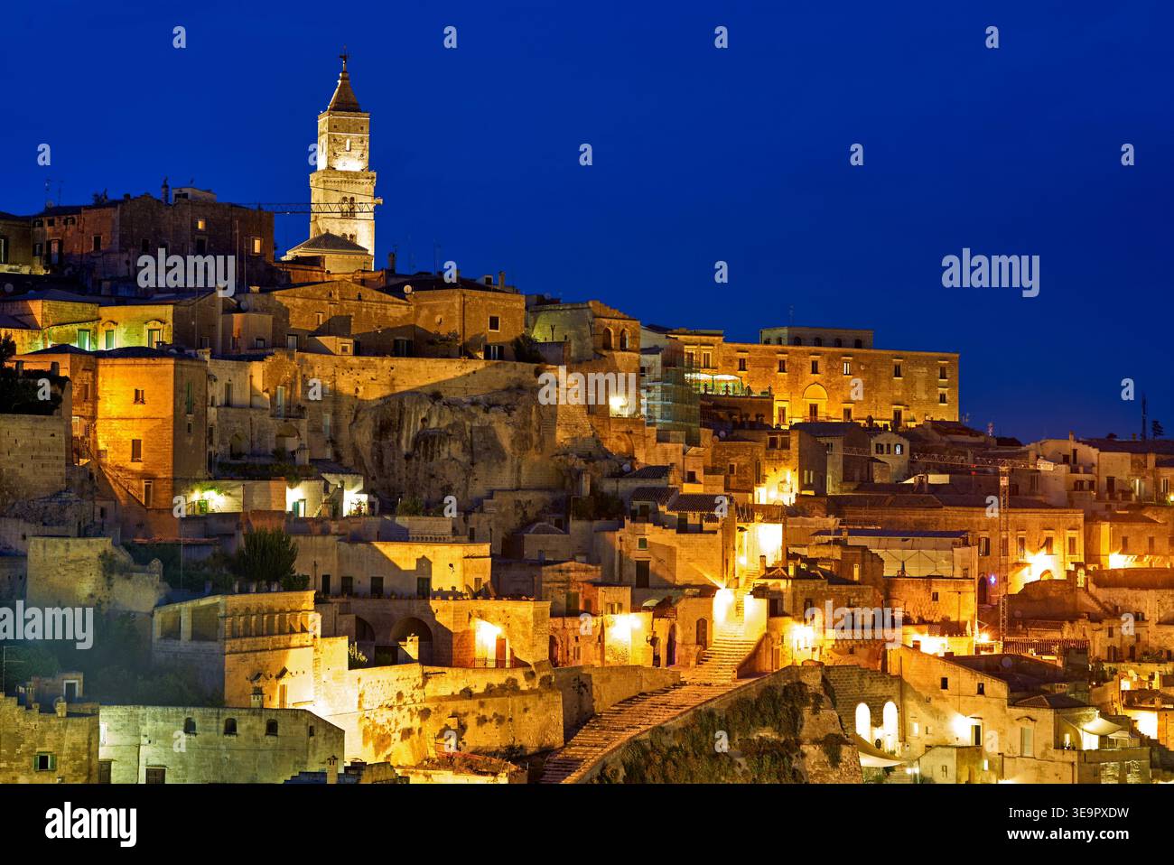 Matera Basilicata mostra gli edifici e le strade mentre il sole tramonta. Le luci della città iniziano a brillare contro il cielo serale. Foto Stock