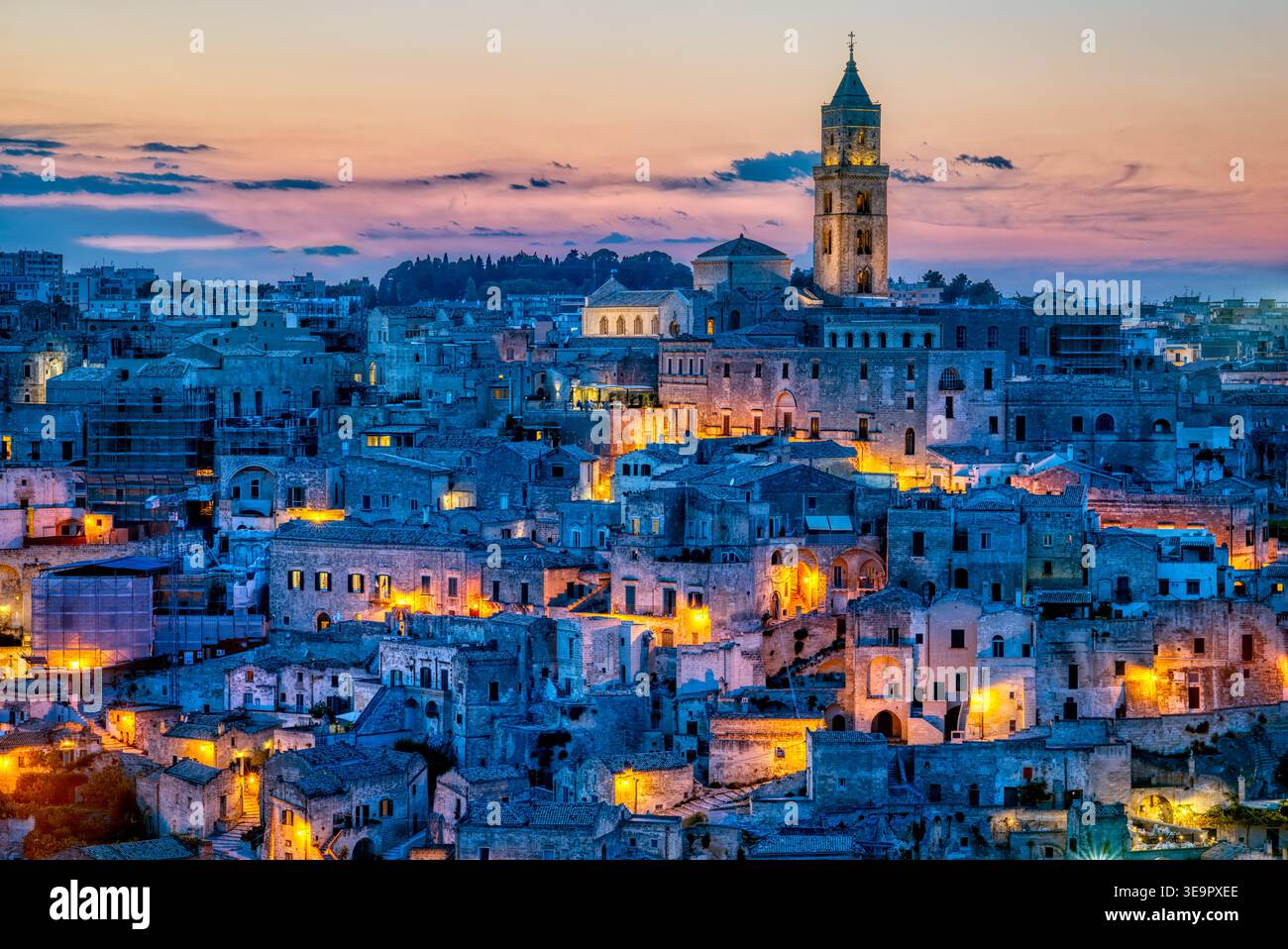 I Sassi di Matera mostrano edifici e strade illuminate al tramonto. Il cielo diventa colorato sulla città antica e sulla sua architettura storica. Foto Stock