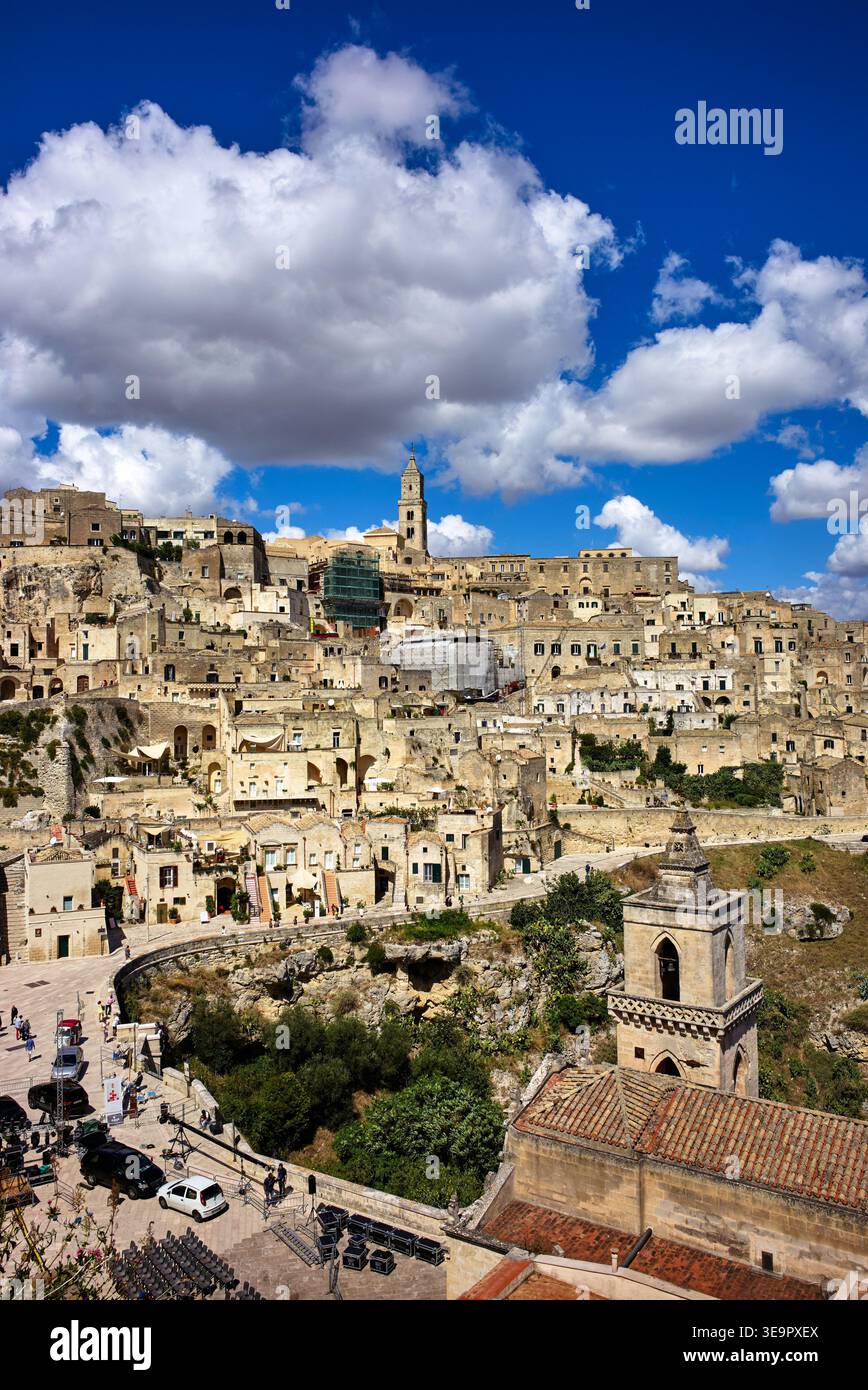 Vista di Matera con antichi edifici in pietra e nuvole. Le persone camminano per le strade e si godono l'atmosfera della città. Foto Stock