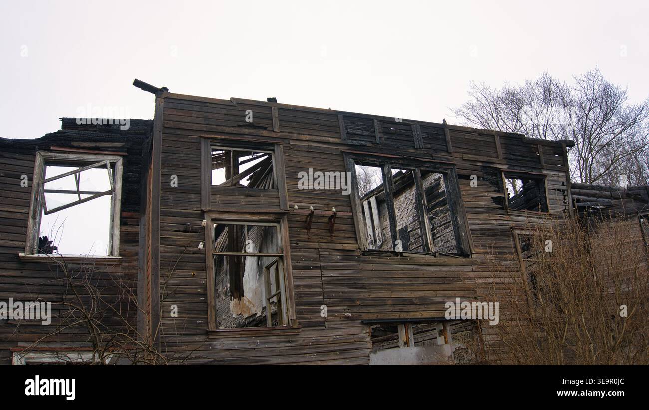 Casa di legno abbandonata rovinata dal fuoco con pareti carbonizzate Foto Stock