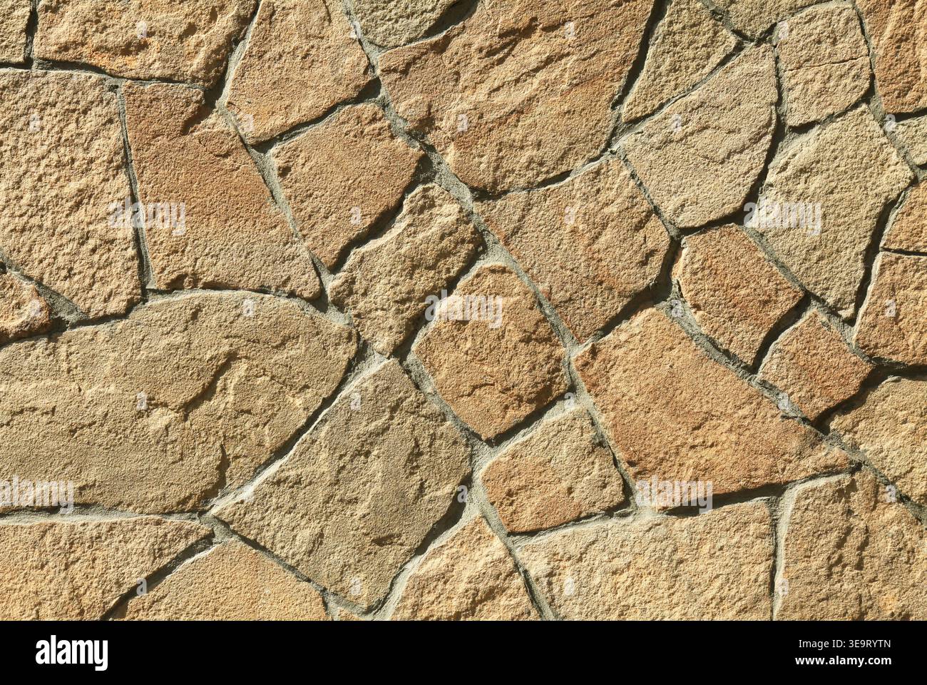 Parete in granito, sfondo, texture. Superficie in muratura caotica di grandi rocce granitiche di colore terracotta. La struttura murale delle pietre vulcaniche marroni. Mod Foto Stock