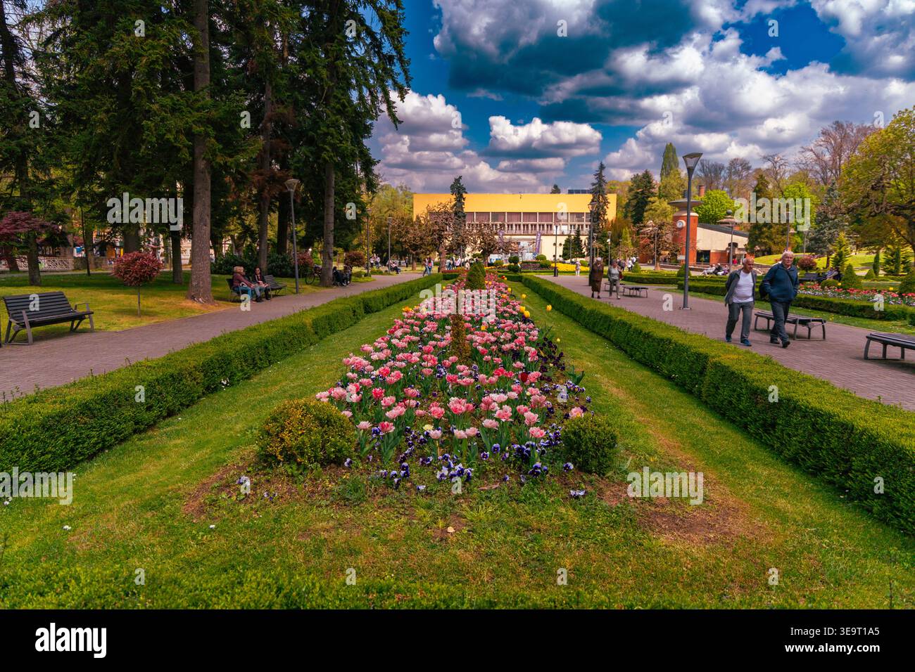 Colorato sentiero con aiuole di fiori e lussureggiante parco cittadino Foto Stock