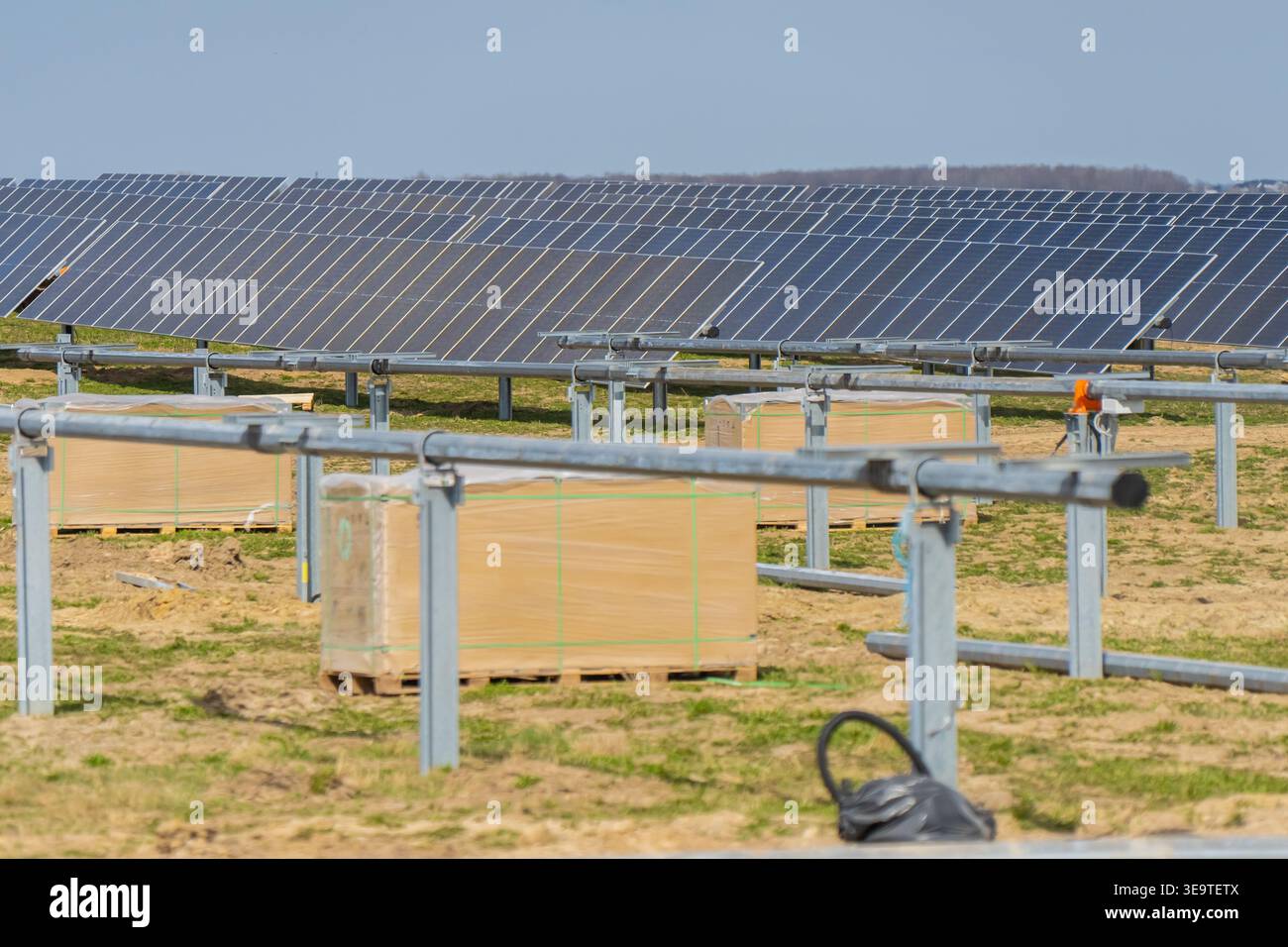 Grande cantiere di impianti solari industriali con file di pannelli fotovoltaici e rack di montaggio in acciaio con pallet per apparecchiature per ener rinnovabile Foto Stock
