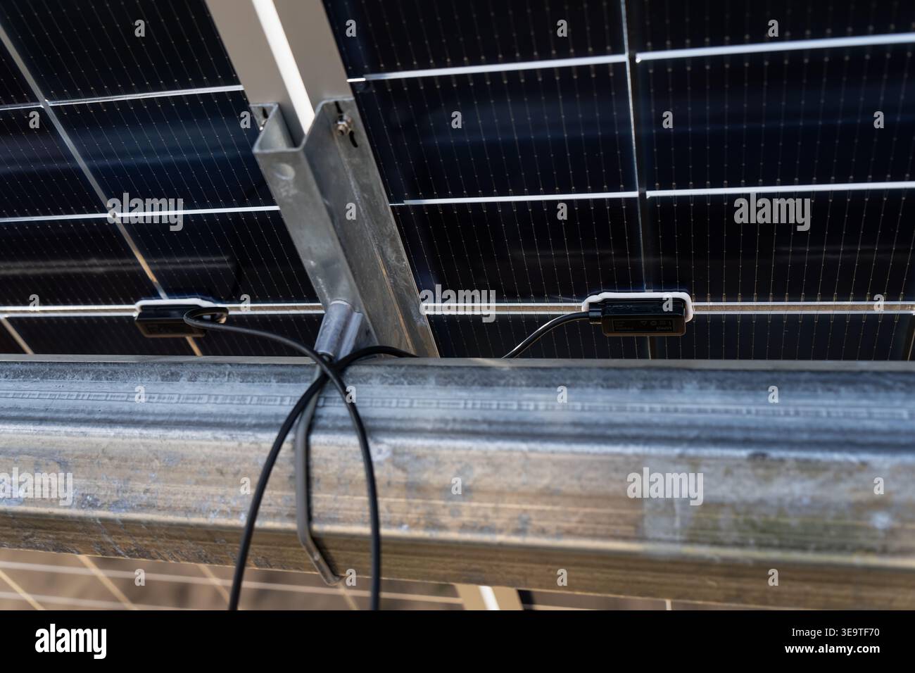 Vista dettagliata della scatola di derivazione del pannello solare e dei connettori del cablaggio elettrico su una struttura di montaggio in metallo per l'alimentazione e l'azienda agricola a energia rinnovabile industriale Foto Stock