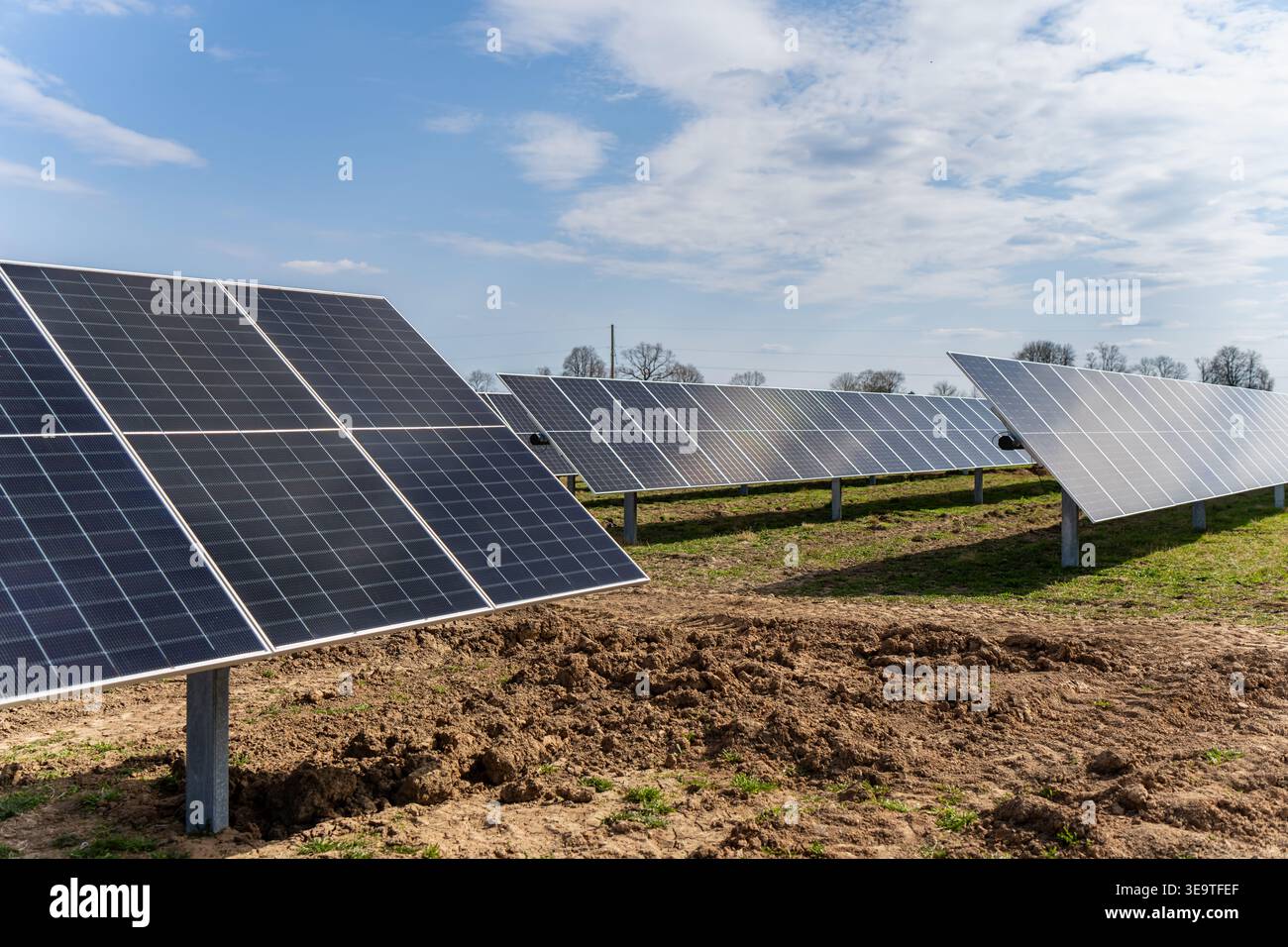 Installazione professionale di array solari in un sito di campagna con pannelli in silicio ad alte prestazioni per investimenti sostenibili ed ecologici Foto Stock