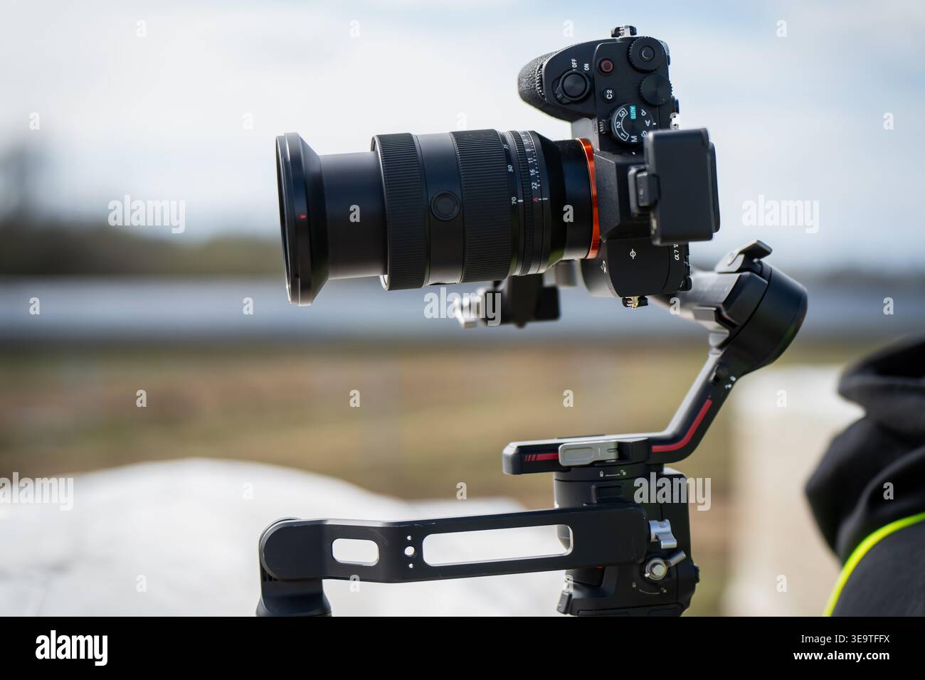 Fotocamera mirrorless professionale con obiettivo grande montato su stabilizzatore elettronico gimbal a 3 assi per una produzione video di alta qualità in un impianto solare industriale Foto Stock