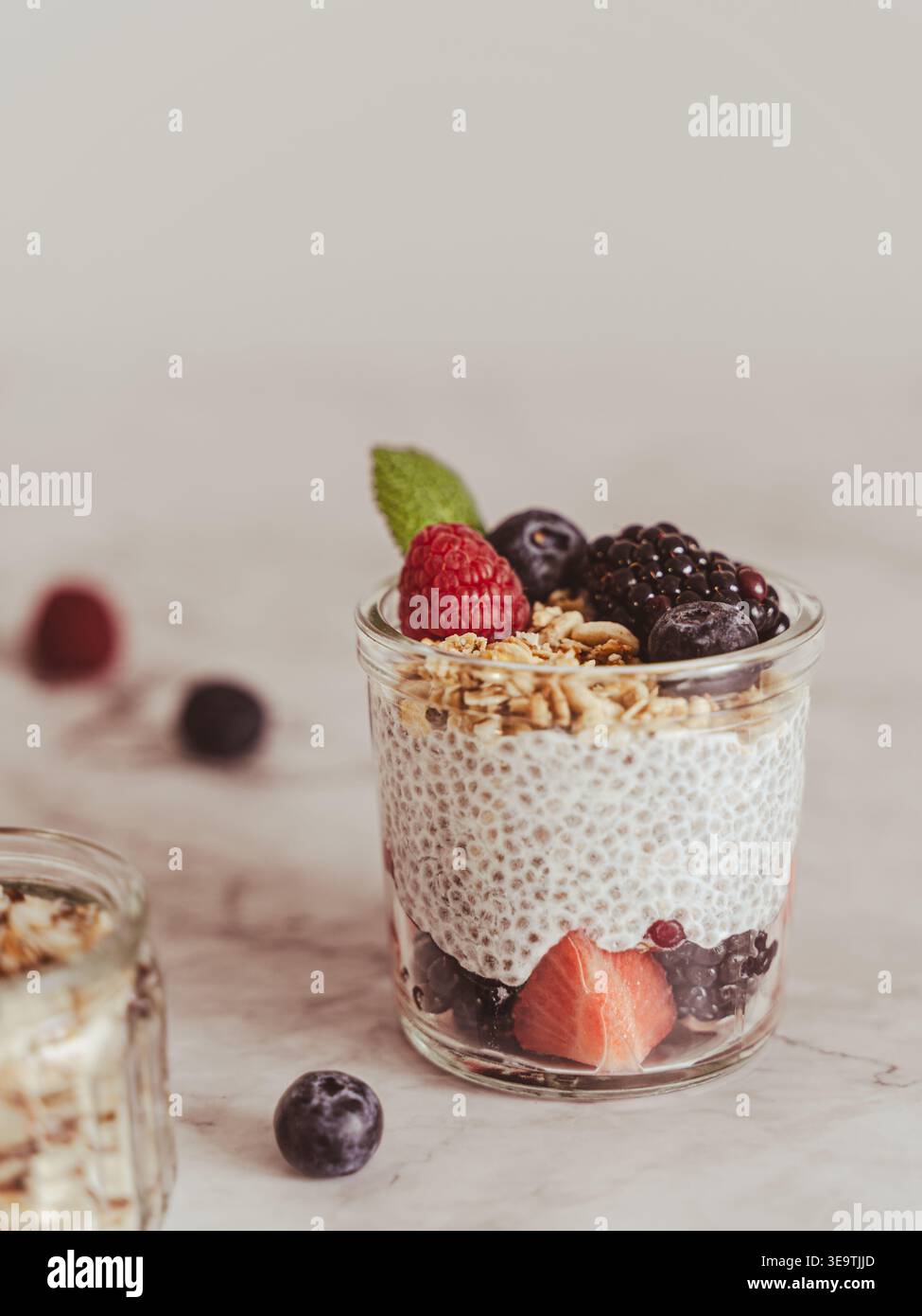 Vista frontale pulita del dolce a strati con bacche e muesli su uno sfondo leggero e minimale Foto Stock