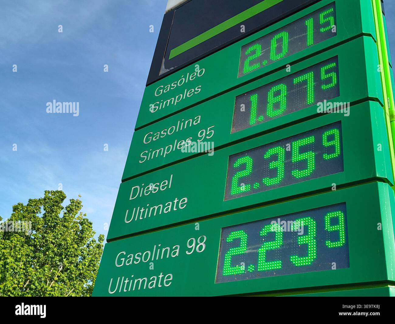 Visualizzazione del prezzo del carburante presso una stazione di servizio che mostra i costi della benzina e del gasolio su un segnale digitale verde brillante contro il cielo blu. Foto Stock