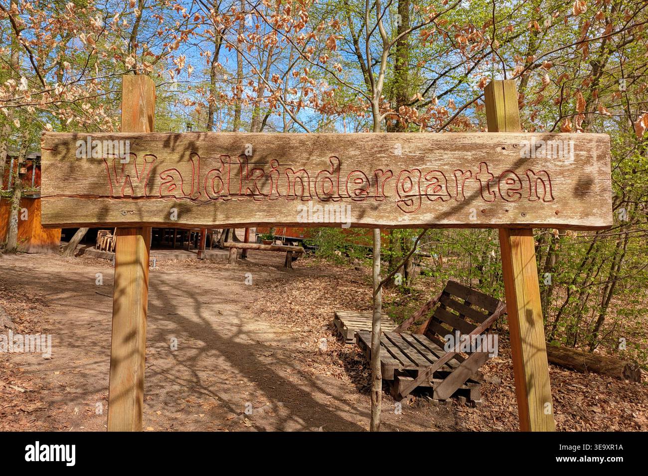 Walldorf, Germania - 7 aprile 2026: Cartello in legno con il testo tedesco “Waldkindergarten” (asilo forestale) in un ambiente forestale. Asilo all'aperto Foto Stock