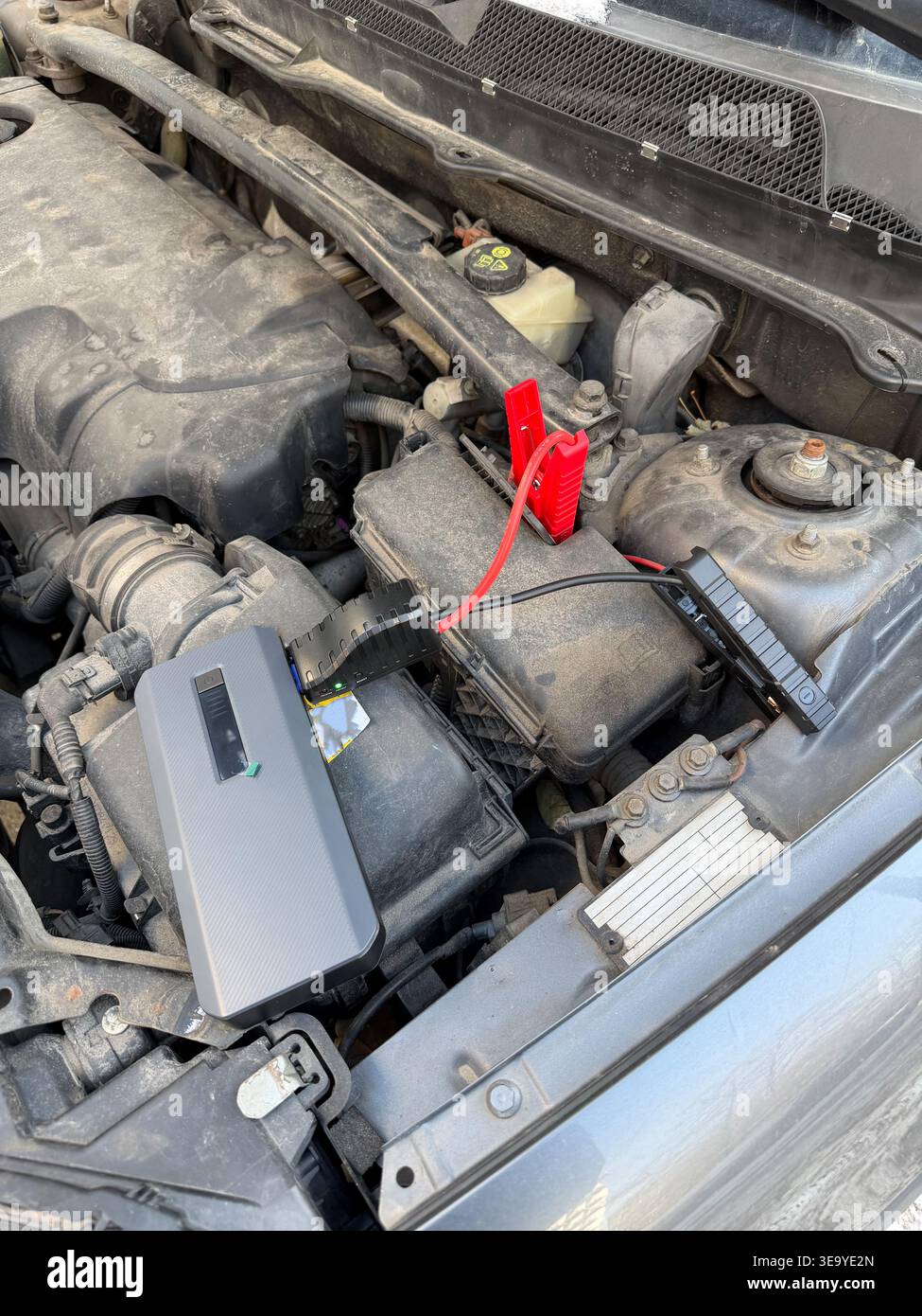 Vista dall'alto e primo piano del dispositivo di avviamento d'emergenza portatile con morsetti rossi e neri collegati al terminale della batteria dell'auto. Dispositivo utilizzato per avviare il veicolo Foto Stock