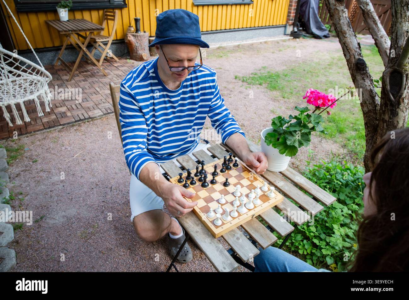 Padre e figlia che giocano a scacchi nel loro cortile in un giorno d'estate. Tempo di qualità in famiglia e sviluppo mentale in un ambiente all'aperto rilassato. Foto Stock