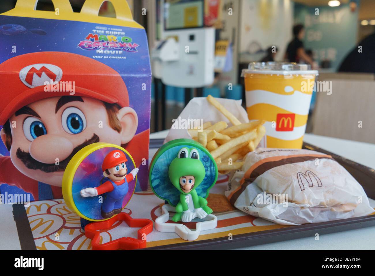 Pasto felice McDonald's con giocattoli promozionali Super Mario, patatine fritte e bevande esposte su un vassoio all'interno di un ristorante affollato a Cebu City, Filippine. Foto Stock