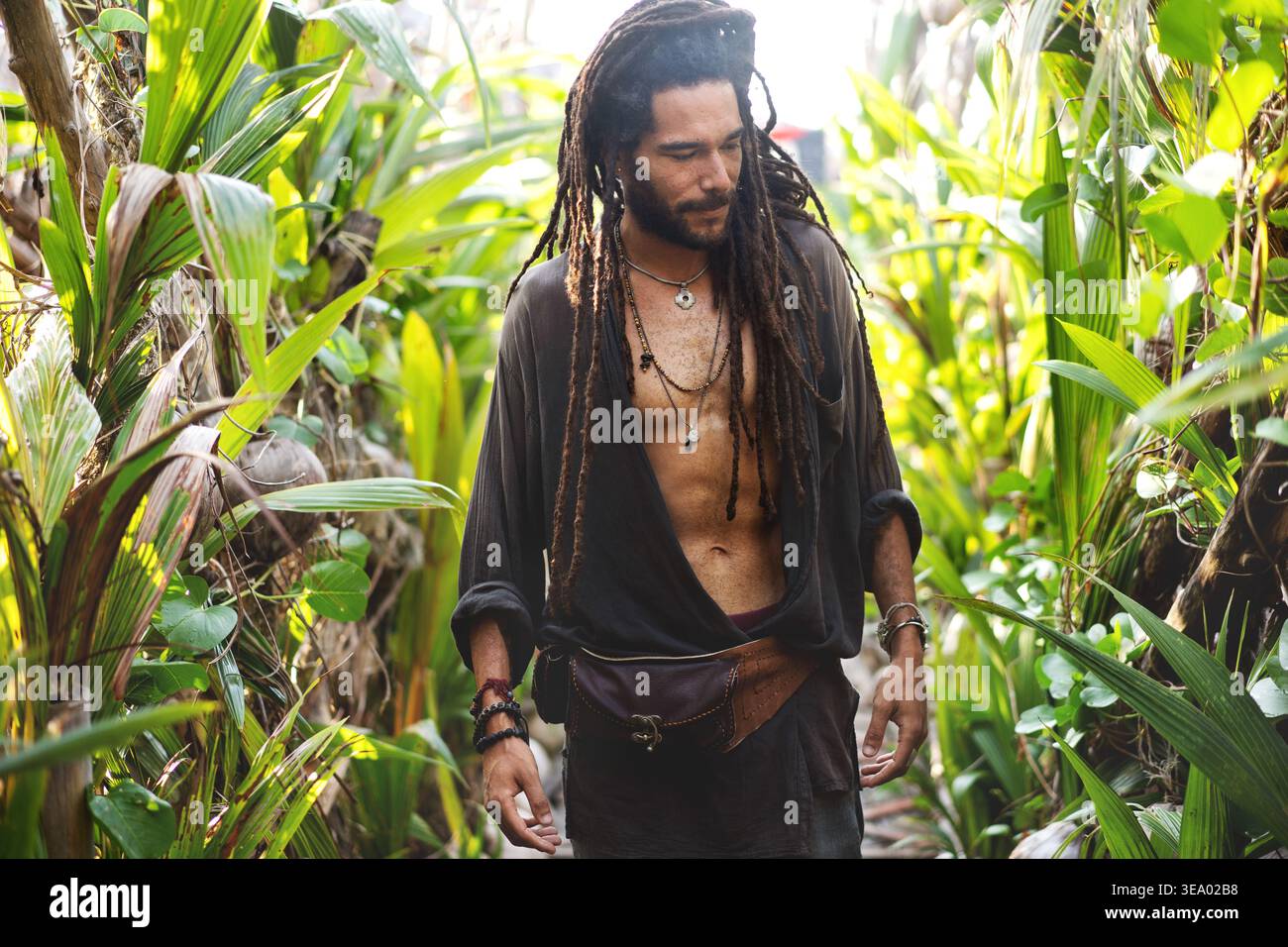 ragazzo alla moda con dreadlocks in palme tropicali sorridenti Foto Stock