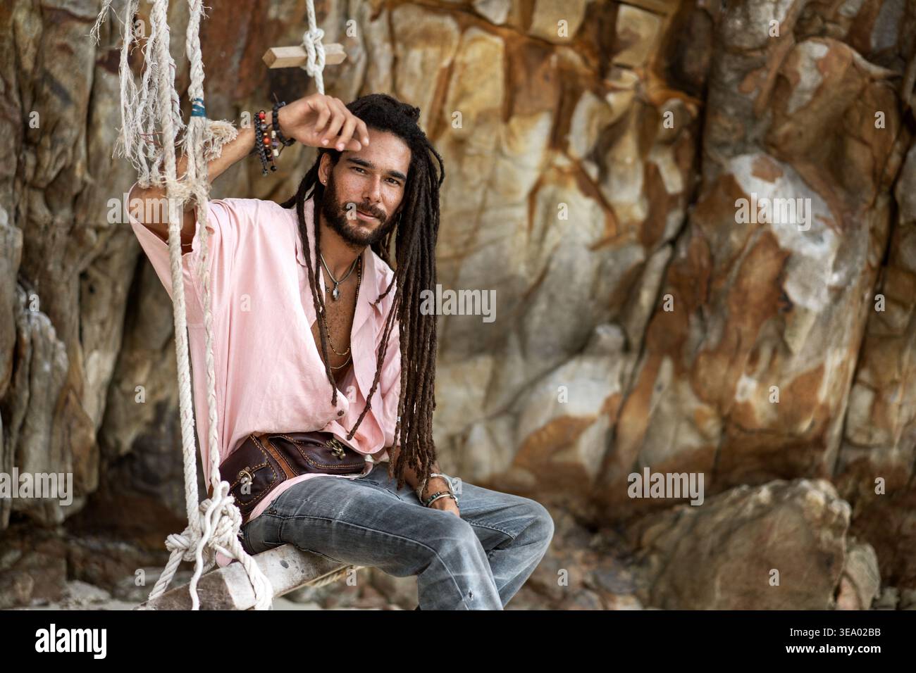 ragazzo europeo con dreadlocks, aspetto asiatico seduto su un swin Foto Stock