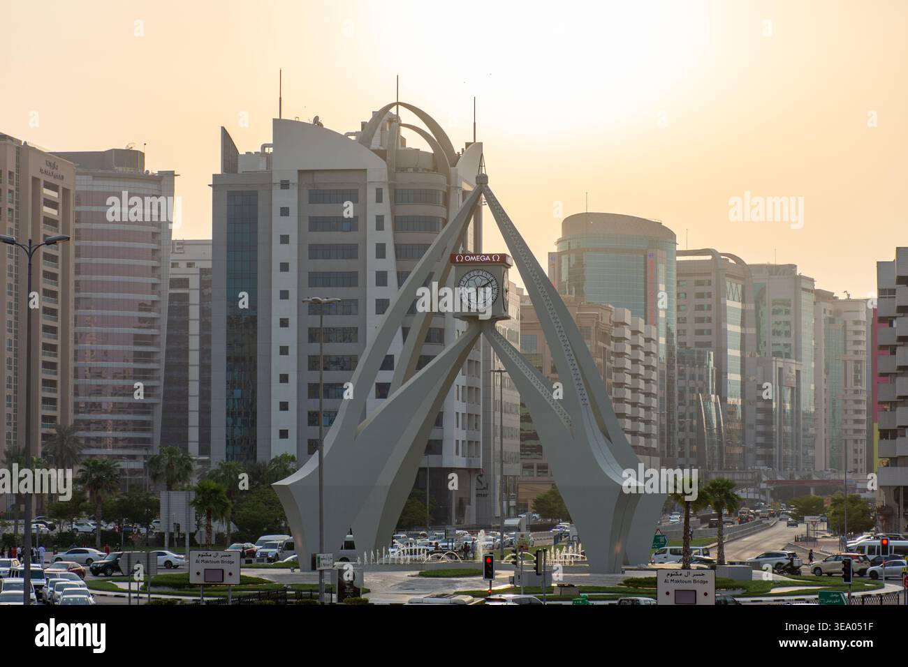 Vista elevata del traffico intenso che si avvicina all'iconico monumento della torre dell'orologio Deira al tramonto a Dubai, Emirati Arabi Uniti. Foto Stock
