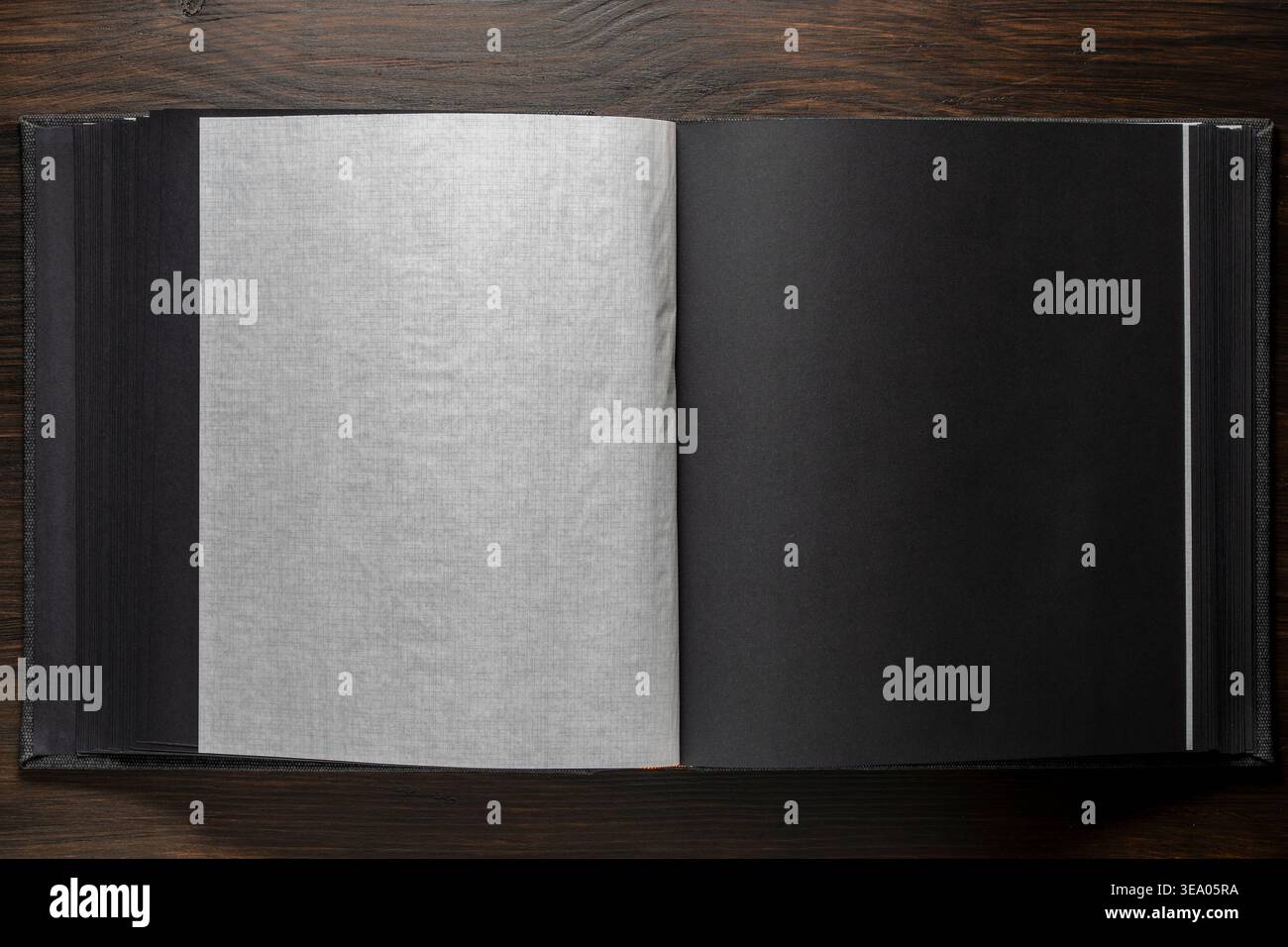 Pagine vuote di album fotografici neri con interfoglie traslucide su legno scuro. Mockup per portafogli di nozze, libri di memoria o eleganti presentazioni di branding. Foto Stock