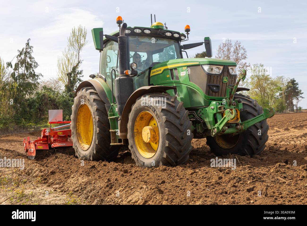 Trattore di medie dimensioni John Deere 6R 185 con erpice Kuhn HR per la preparazione intensiva del letto di semina. Shottisham, Suffolk, Inghilterra, Regno Unito Foto Stock