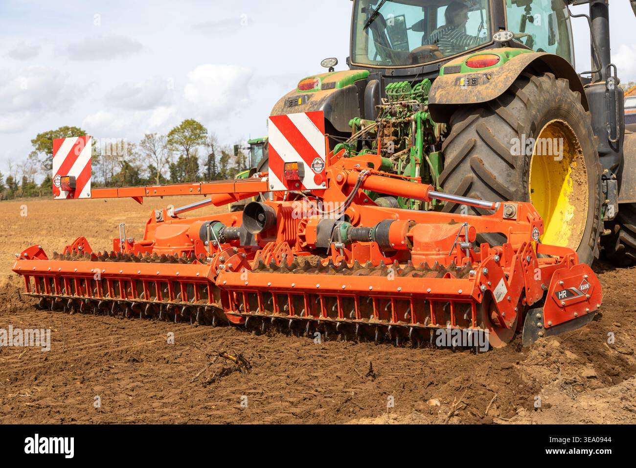 Trattore di medie dimensioni John Deere 6R 185 con erpice Kuhn HR per la preparazione intensiva del letto di semina. Shottisham, Suffolk, Inghilterra, Regno Unito Foto Stock