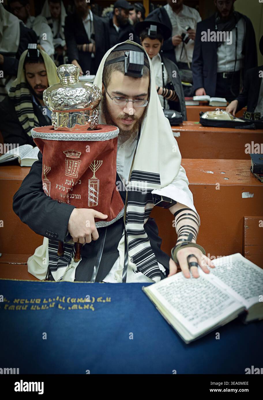 Un adoratore che tiene una piccola Torah durante le preghiere mattutine nei giorni feriali presso la sede centrale di Chabad Lubavitch a Brooklyn, New York Foto Stock