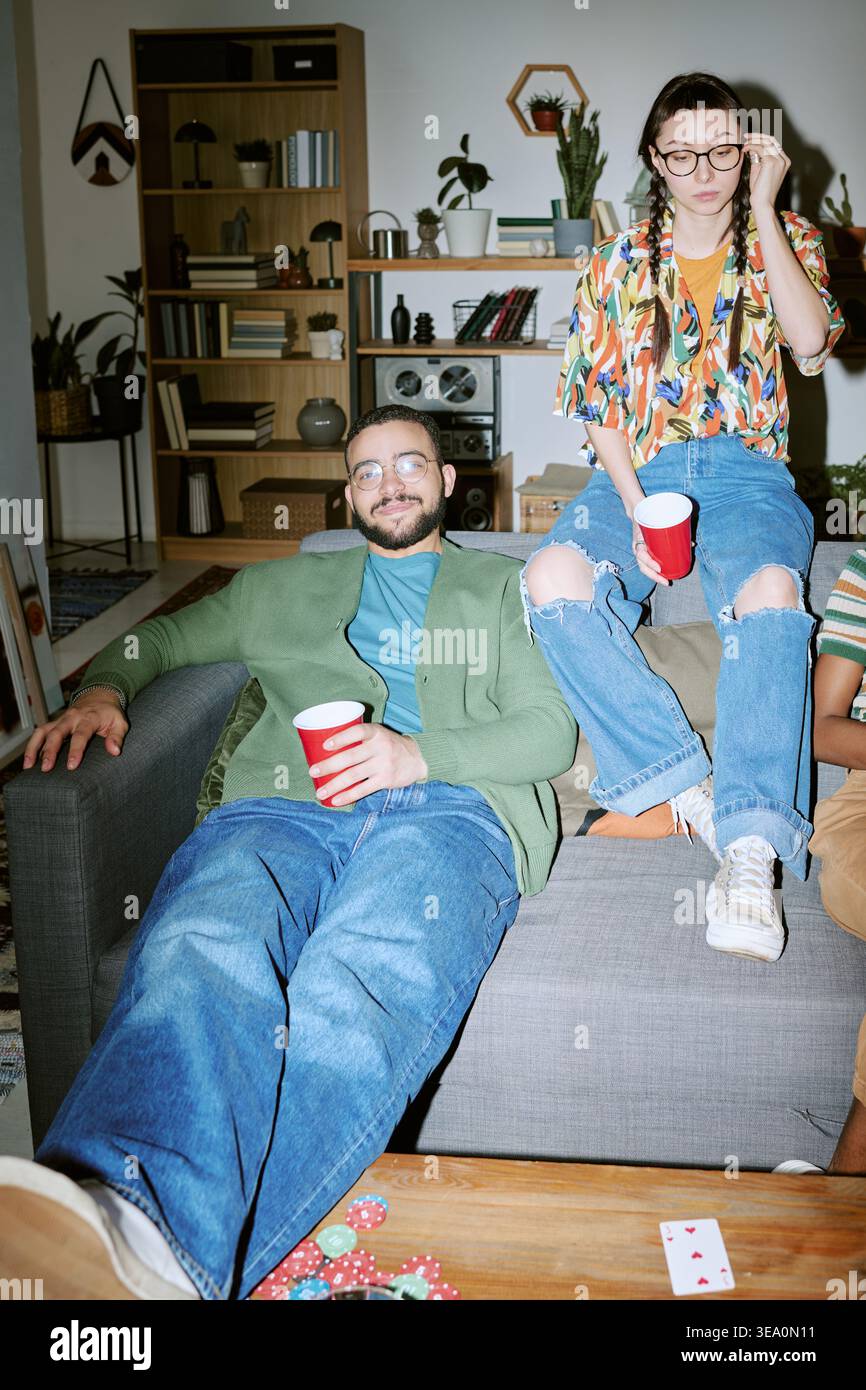 Amici adulti che si rilassano all'House Party con bevande e giochi di carte Foto Stock