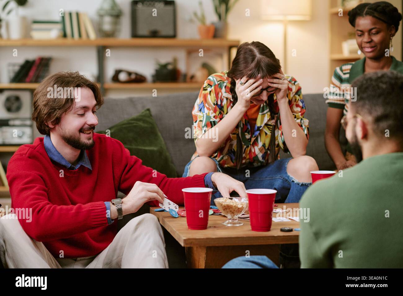 Amici diversi che giocano a carte durante la serata casalinga casuale Foto Stock