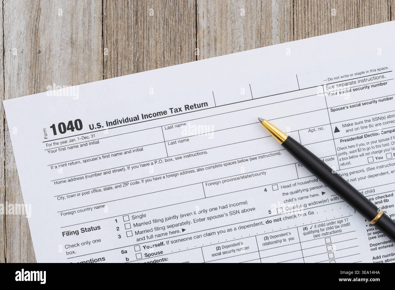 Modulo di dichiarazione dei redditi individuali US 1040 con penna su sfondo di una scrivania in legno che rappresenta il deposito fiscale, la contabilità e la documentazione finanziaria. Foto Stock