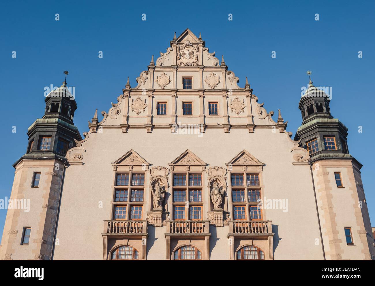 Storica facciata neorinascimentale dell'edificio del Collegium Minus con grande tetto a spioventi, statue decorative e torri gemelle su un cielo azzurro. Foto Stock
