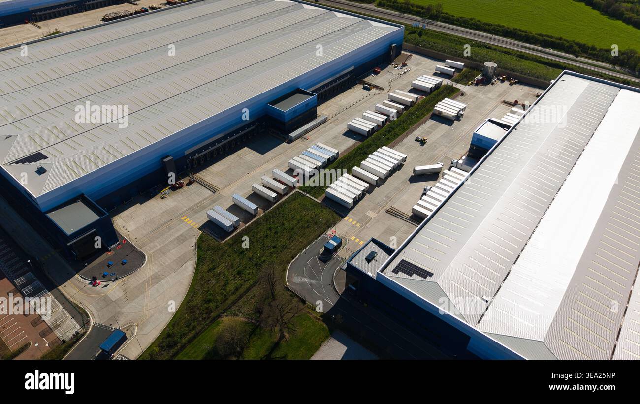 Vista aerea di grandi magazzini industriali e file di semirimorchi bianchi presso le banchine di carico di Magna Park, Inghilterra, Regno Unito. Foto Stock