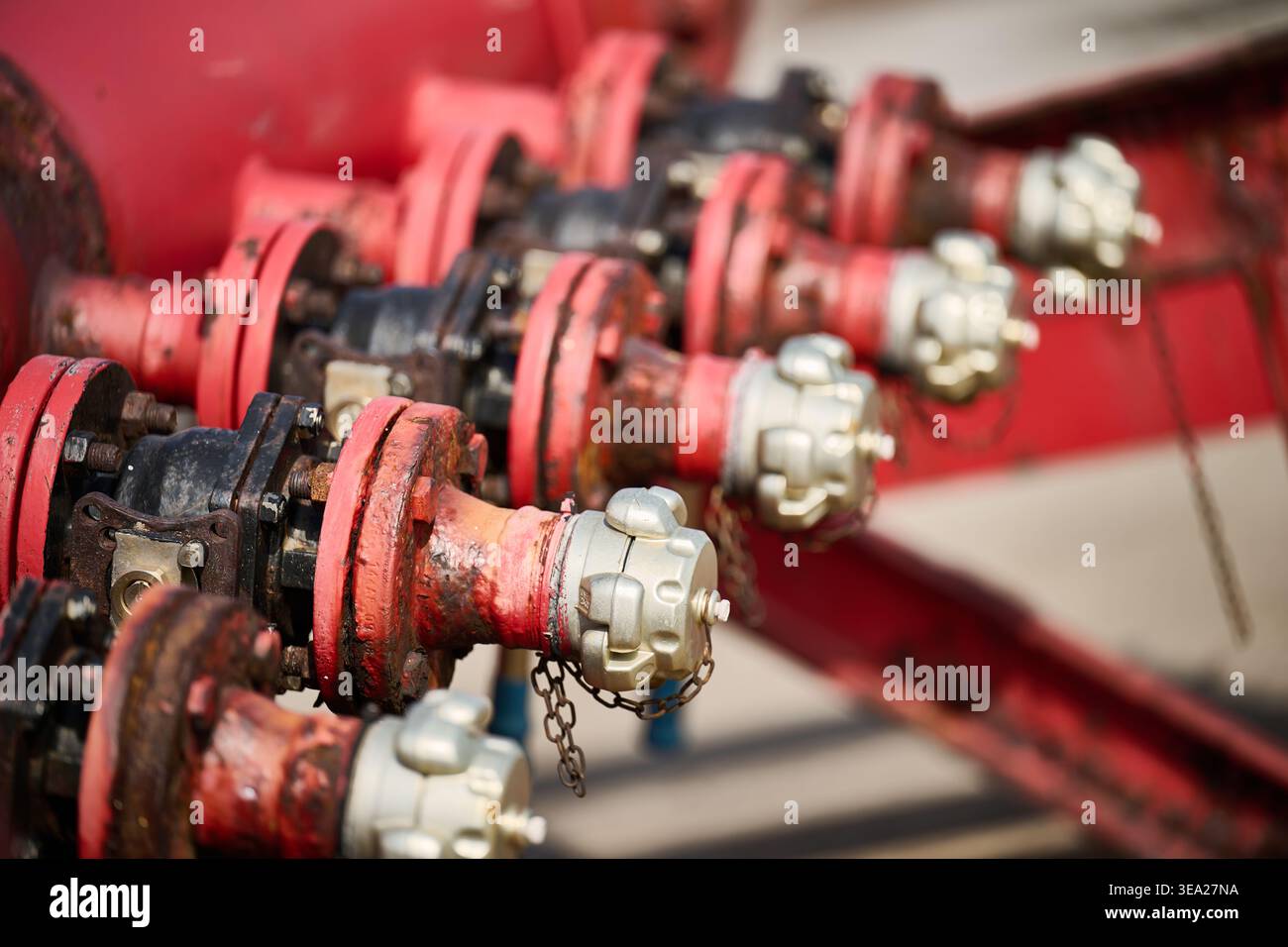 Punti di collegamento industriali rossi con più agenti atmosferici con tappi argentati, che formano un collettore per il trasferimento di liquidi o gas Foto Stock