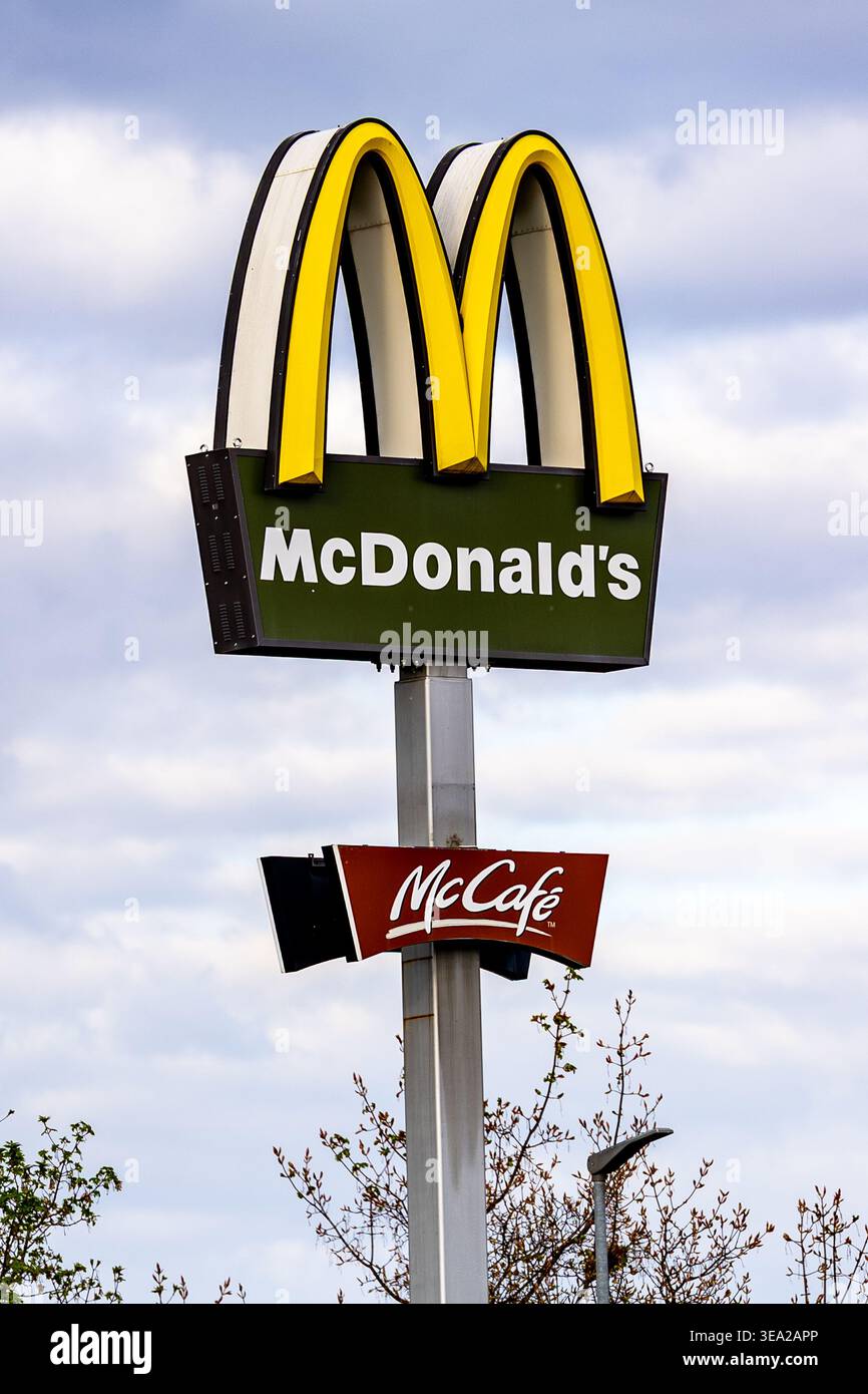 Il cartello di McDonald's con archi dorati e il logo McCafé contro il cielo nuvoloso in Germania, che illustra il marchio globale del fast food. Foto Stock