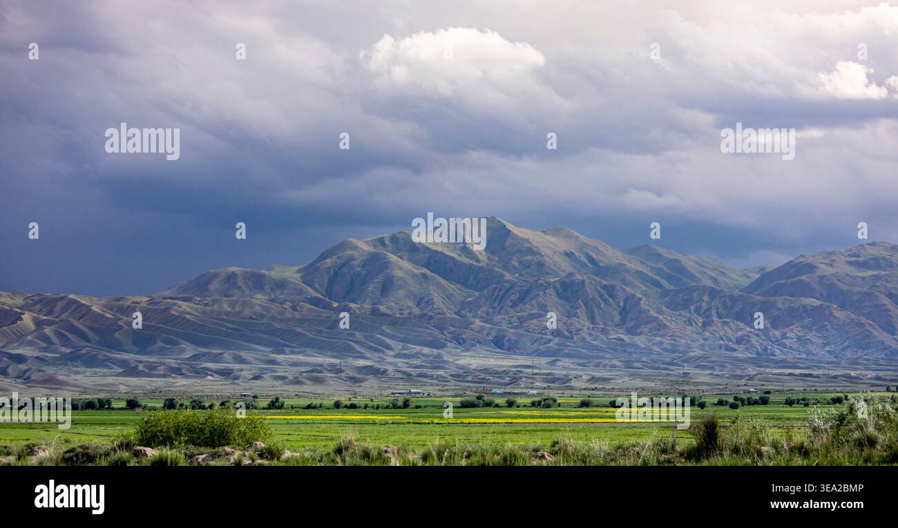 Montagne e valle con terreni agricoli lungo il confine tra Kirghizistan e Kazakistan in Asia centrale. Foto Stock