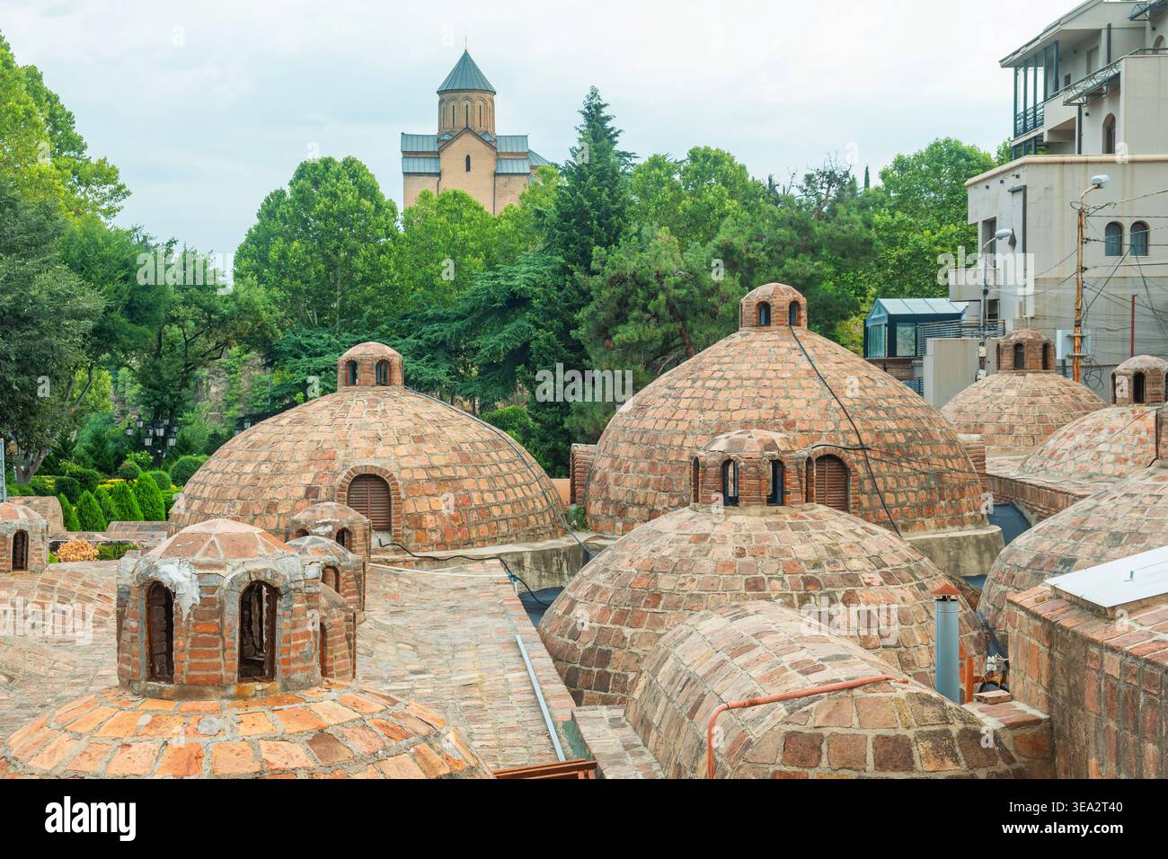 Cupole per bagni di zolfo nel quartiere di Abanotubani con verdi colline ed edifici storici nel centro storico di Tbilisi, Georgia. Architettura tradizionale integrata Foto Stock