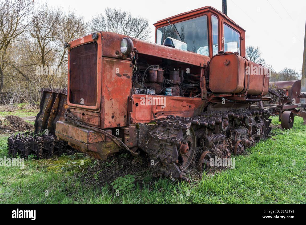 Trattore cingolato arrugginito abbandonato nell'erba, vecchio concetto di macchinari agricoli per l'agricoltura, il patrimonio rurale, l'industria, il restauro, il decadimento meccanico. Foto Stock