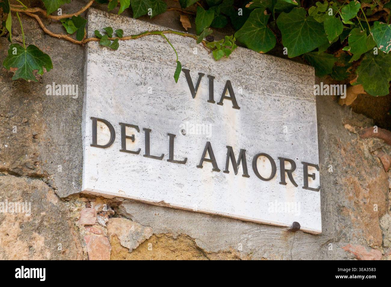 Cartello stradale in marmo di via dell'amore, su una facciata di un edificio a Pienza, in Toscana Foto Stock
