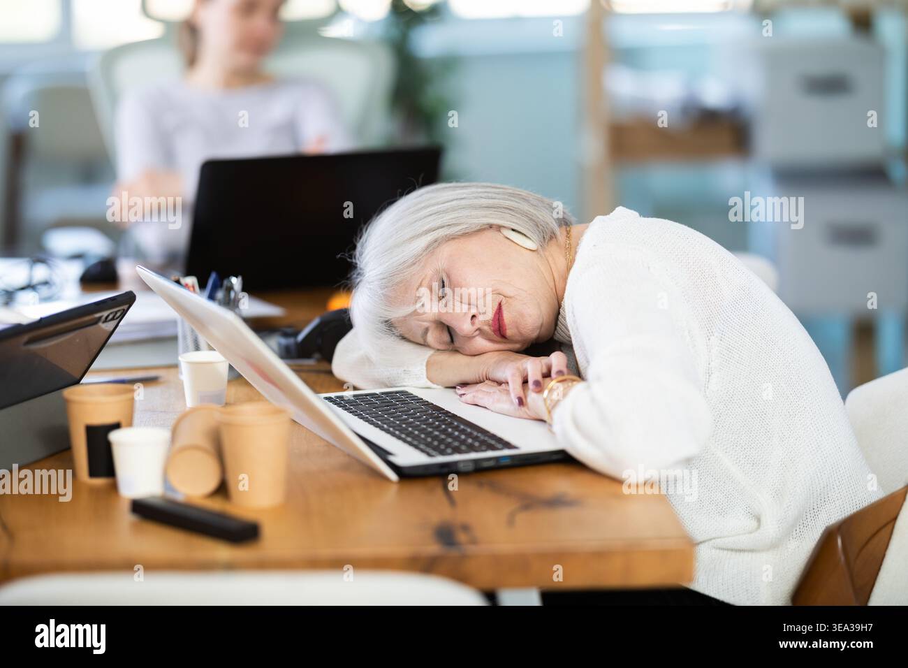 Le donne stanche dormono accanto al computer al lavoro. Foto Stock