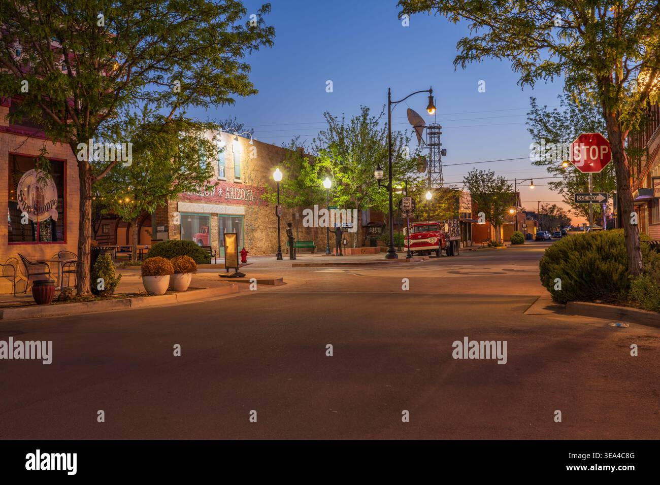 Un camioncino a pianale rosso vintage parcheggiato al Standin' on the Corner Park lungo la storica Route 66 a Winslow, Arizona, al crepuscolo. Foto Stock