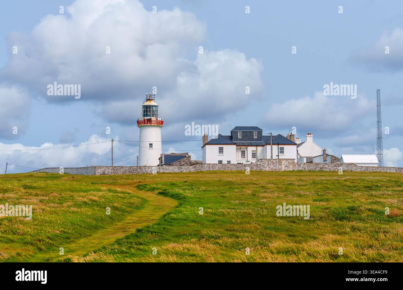 Faro di Loop Head e abitazioni dei guardiani del faro con visitatori sulla galleria della lanterna e un ex traliccio DGPS all'inizio dell'estate, Contea di Clare, Irlanda. Foto Stock