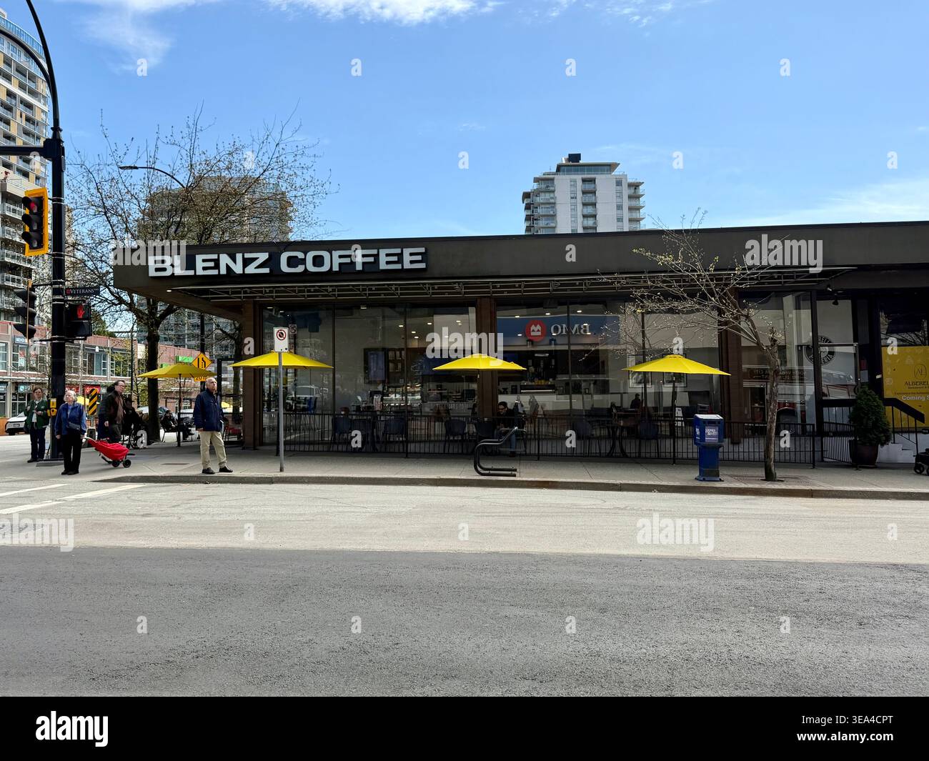 Vista sulla strada di una caffetteria Blenz con patio all'aperto e ombrelloni gialli a Vancouver, British Columbia, Canada. Fatto il 21 aprile 2026. Foto Stock