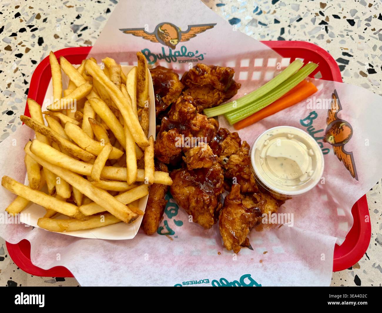 VANCOUVER, BC - 21 APRILE 2026: Ali di pollo e patatine fritte Buffalo's Express servite in un ristorante Fatburger. Fotografia editoriale di cibo e ristoranti. Foto Stock