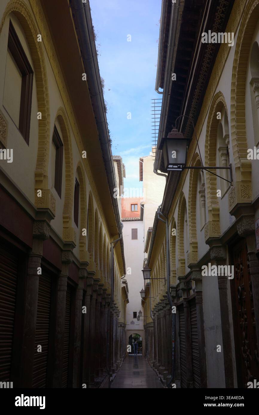 Vicolo vuoto del Alcaicería, lo storico bazar moresco di Granada, fiancheggiato da facciate ornate con arcate in gesso decorativo e persiane chiuse Foto Stock