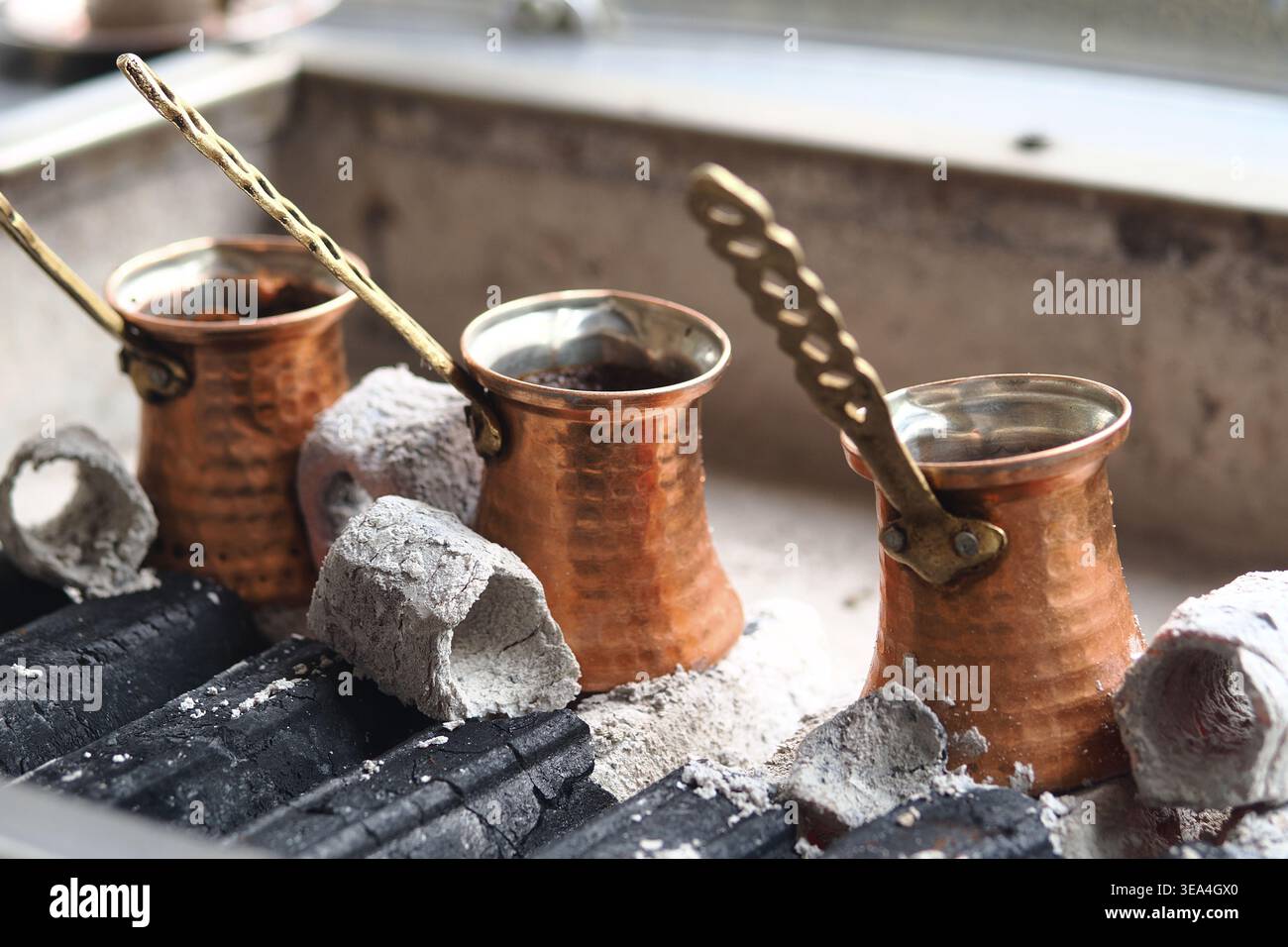 Preparare caffè turco con pentole di rame su carboni caldi in cucina Foto Stock