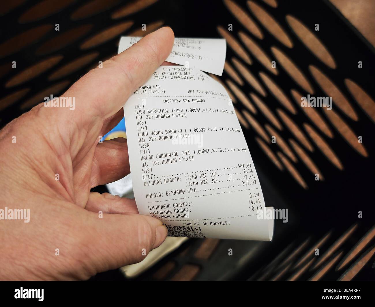 Kirov, Russia - 12 aprile 2026: Una mano contiene una ricevuta di un negozio che elenca vari articoli acquistati in un supermercato, mostrando le spese totali e il pagamento conf Foto Stock