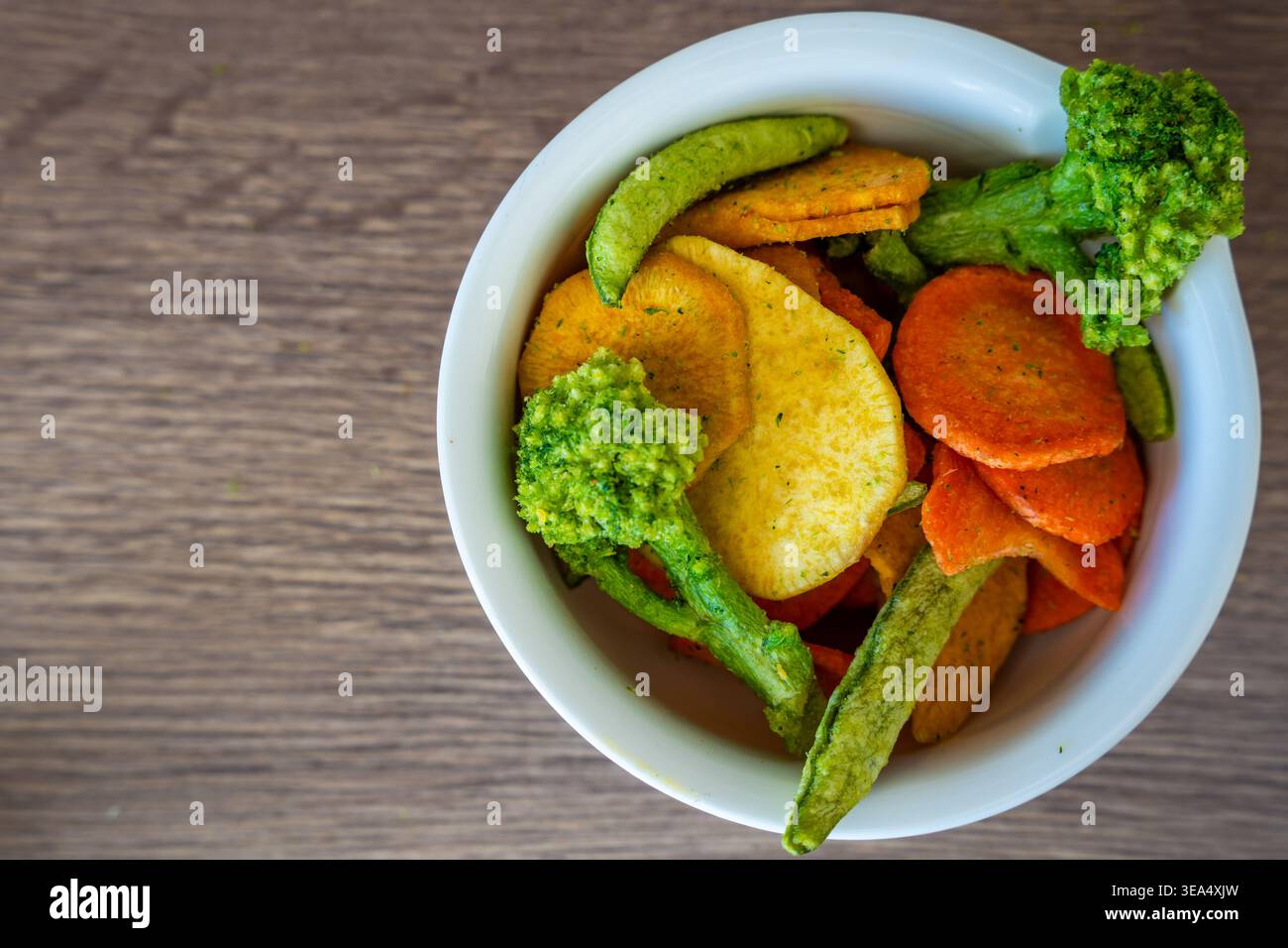 Frittelle di verdure miste in recipiente con broccoli, carote, piselli e patate dolci su un tavolo di legno. Spuntino sano e concetto di mangiare pulito senza sale e zucchero Foto Stock