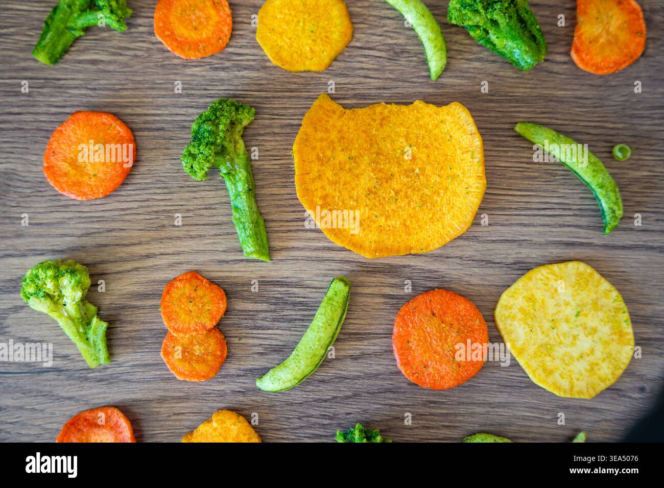 Fantasia senza cuciture di patatine vegetali con broccoli piselli di carota e patate dolci su fondo di legno. Consistenza sana dello spuntino e concetto di mangiare pulito. Foto Stock