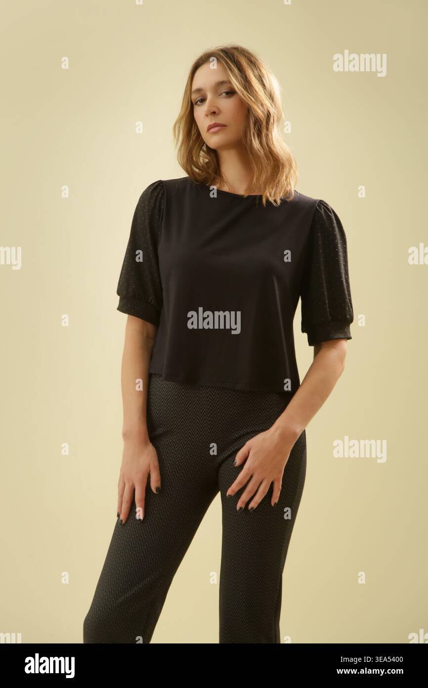 Ritratto della moda da studio di donna con Top a manica corta nero e pantaloni neri sottili: Un look casual elegante e raffinato Foto Stock