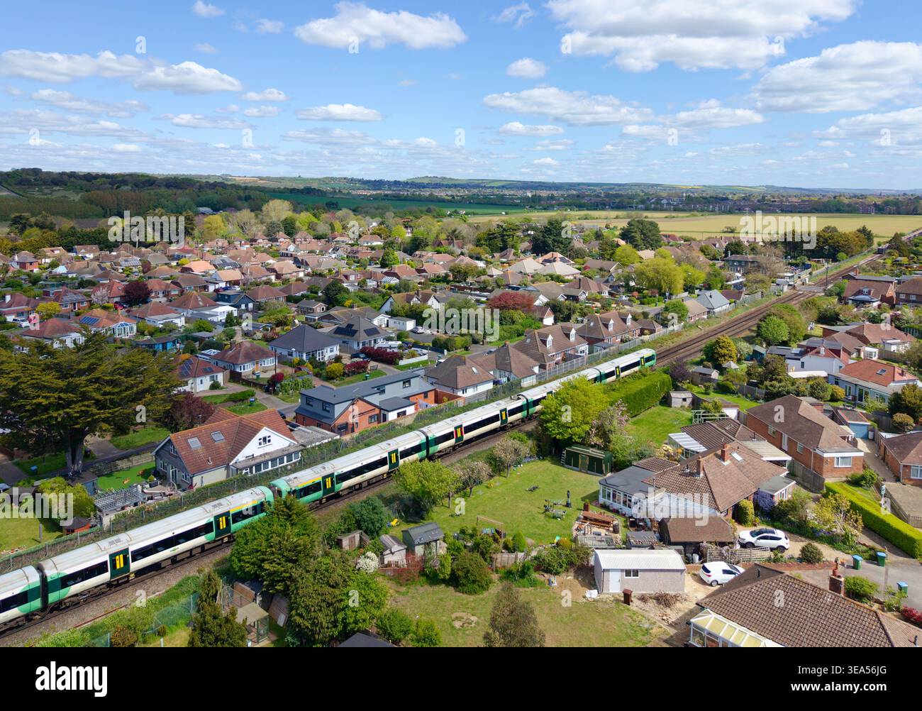 Treno Electrostar classe 377 della Southern Rail, vista aerea con droni, viaggiando su binari ferroviari attraverso abitazioni residenziali a Ferring, West Sussex, Regno Unito. Foto Stock