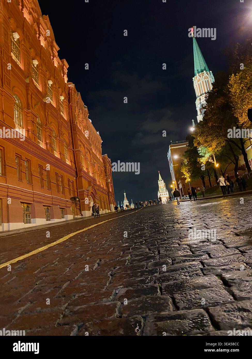 Mosca, Russia - 23 ottobre 2020: Vista notturna della Piazza Rossa con mura e torri del Cremlino, edifici storici illuminati e persone che camminano su ciottoli - Immagine stock catturata con smartphone