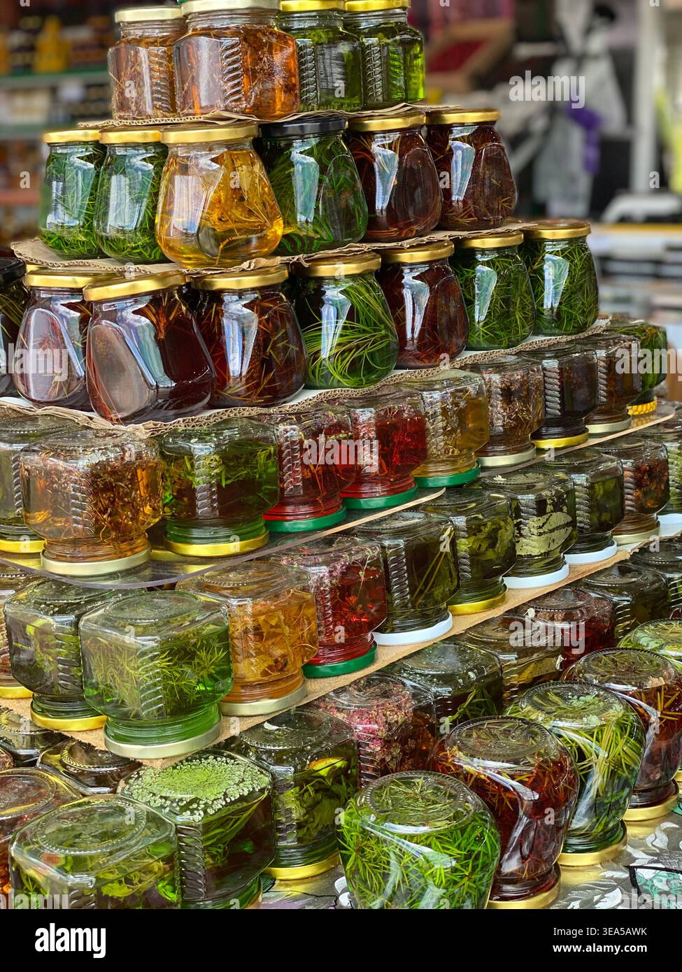Giare colorate con infusioni di erbe e piante conservate esposte al mercato locale - Immagine stock catturata con smartphone
