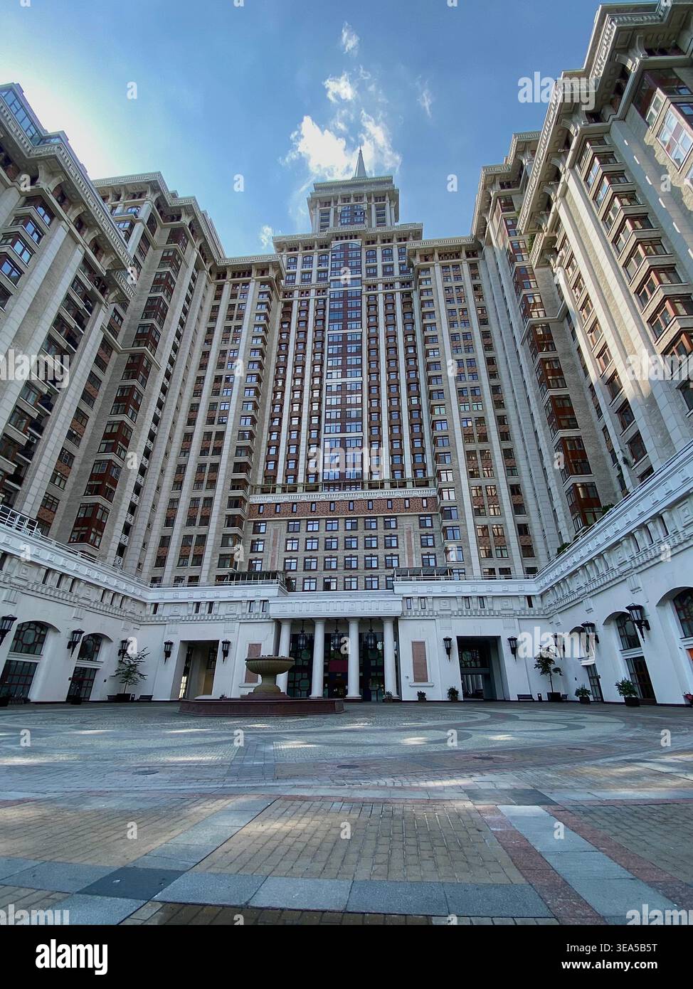 Mosca, Russia - giugno 27 2021: Vista simmetrica del cortile di un moderno edificio residenziale con elementi architettonici classici e sfondo blu del cielo - Immagine stock catturata con smartphone